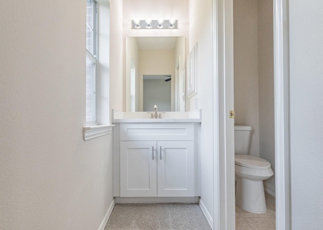 bathroom featuring vanity, baseboards, a textured wall, and toilet