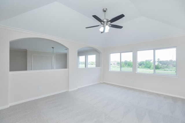 empty room with ornamental molding, lofted ceiling, light carpet, baseboards, and a ceiling fan