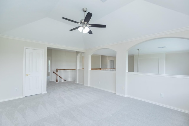 carpeted spare room featuring baseboards, ceiling fan, arched walkways, and lofted ceiling