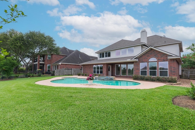 back of property featuring a fenced backyard, a chimney, brick siding, a pool with connected hot tub, and a yard