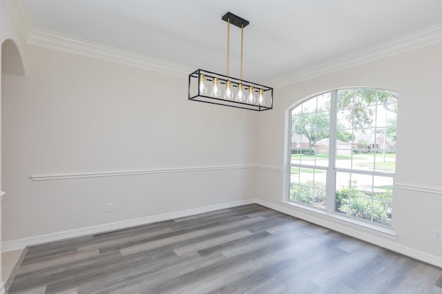 unfurnished dining area featuring crown molding, baseboards, arched walkways, and wood finished floors