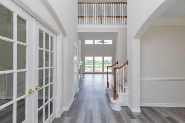 foyer entrance with ceiling fan, arched walkways, a high ceiling, and wood finished floors