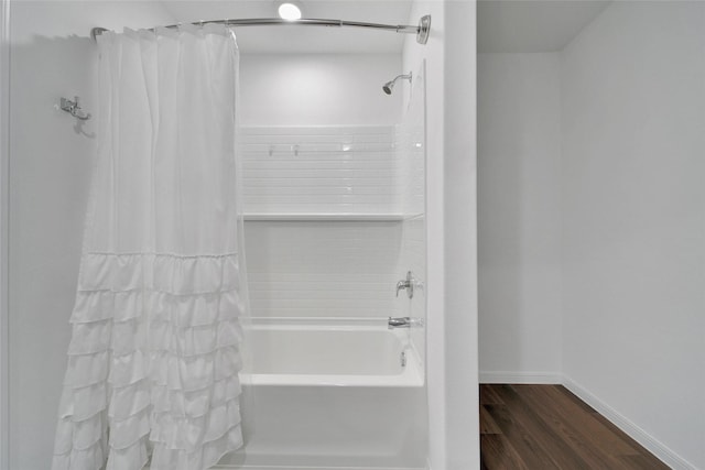 bathroom featuring shower / bathtub combination with curtain, wood finished floors, and baseboards