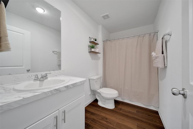 full bathroom featuring toilet, vanity, visible vents, and wood finished floors