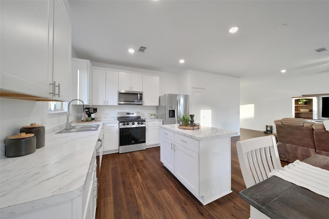 kitchen with a sink, dark wood-type flooring, visible vents, open floor plan, and appliances with stainless steel finishes