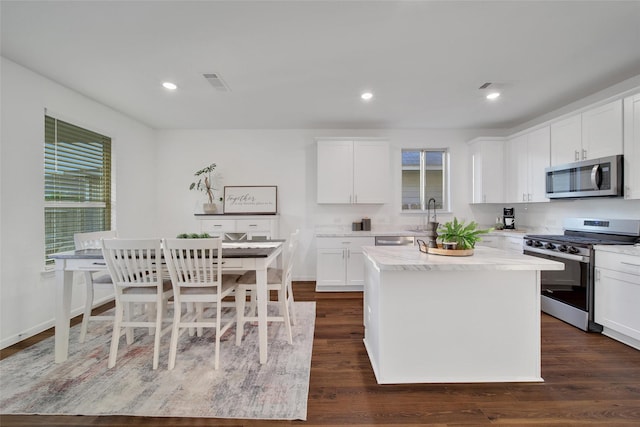 16322 Fontana Ct, Conroe, TX 77302 - kitchen featuring stainless steel appliances, dark wood-type flooring, white cabinetry, a center island, and recessed lighting