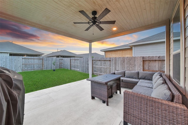 patio terrace at dusk featuring a fenced backyard, ceiling fan, an outdoor living space, and a yard