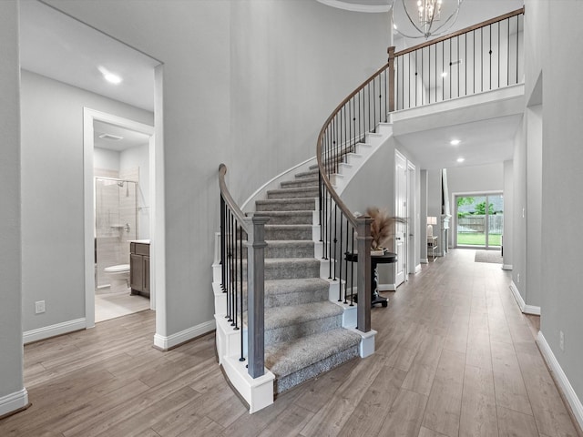16926 Grayson Woods Ln, Humble, TX 77346 - stairway featuring baseboards, a chandelier, wood finished floors, and a towering ceiling