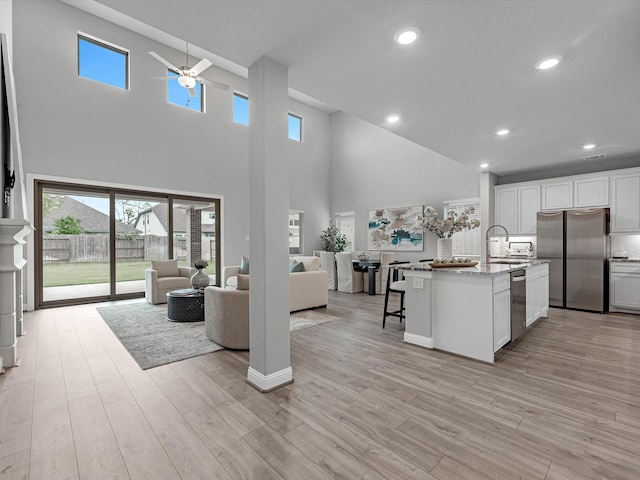 16926 Grayson Woods Ln, Humble, TX 77346 - kitchen featuring white cabinets, appliances with stainless steel finishes, a ceiling fan, open floor plan, and a towering ceiling