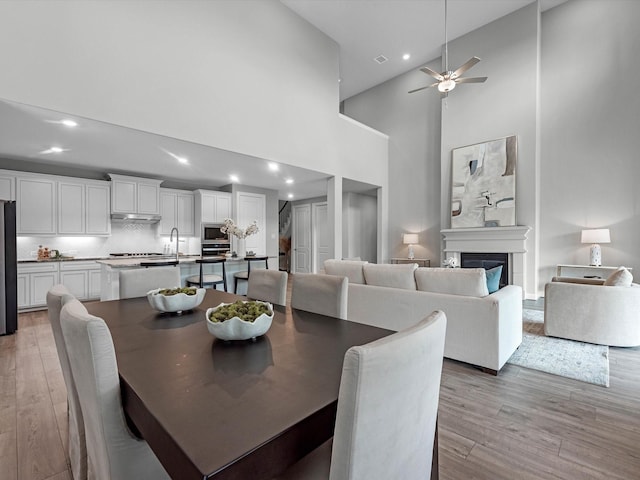16926 Grayson Woods Ln, Humble, TX 77346 - dining space featuring light wood-style floors, a glass covered fireplace, recessed lighting, and a towering ceiling