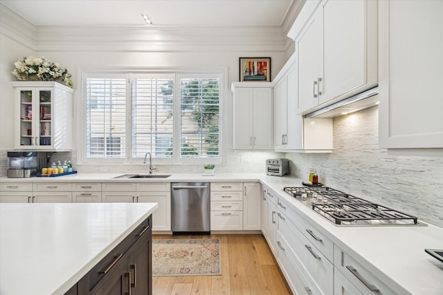 kitchen with a sink, appliances with stainless steel finishes, white cabinetry, and light countertops