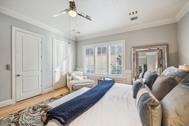 bedroom featuring a ceiling fan, visible vents, ornamental molding, and light wood-style flooring