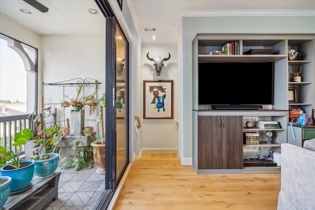 interior space featuring visible vents, ornamental molding, light wood-style flooring, and baseboards