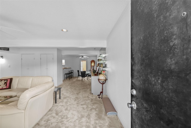 living room with a ceiling fan, visible vents, and light carpet
