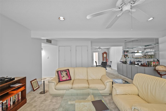 living area with carpet floors, a textured ceiling, ceiling fan, and visible vents