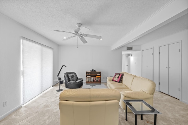 living room with visible vents, a textured ceiling, ceiling fan, and light colored carpet