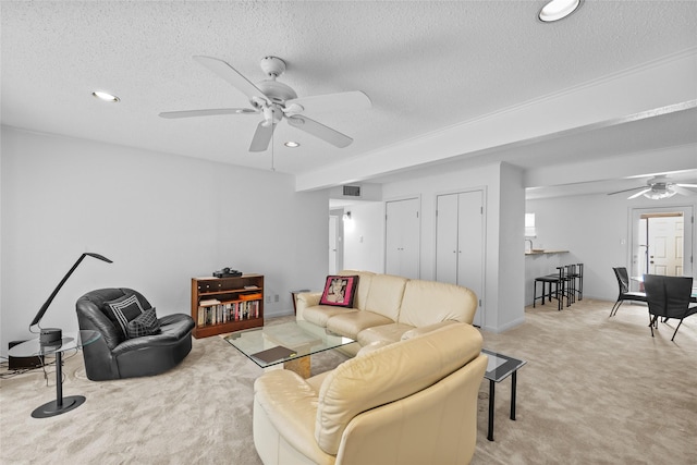 living room featuring light colored carpet, a textured ceiling, and ceiling fan