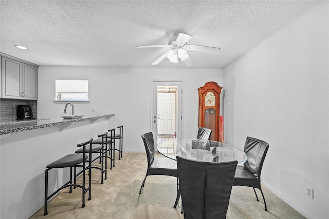 dining area featuring a ceiling fan, a textured ceiling, light carpet, and baseboards