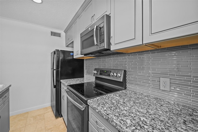 kitchen featuring dark stone counters, stainless steel appliances, baseboards, and visible vents
