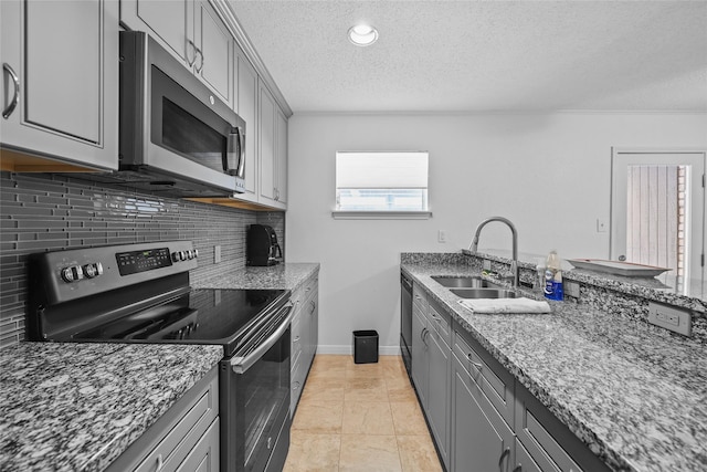 kitchen with a sink, a textured ceiling, appliances with stainless steel finishes, and gray cabinetry