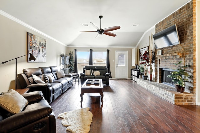 living room featuring a ceiling fan, vaulted ceiling, a brick fireplace, wood finished floors, and ornamental molding