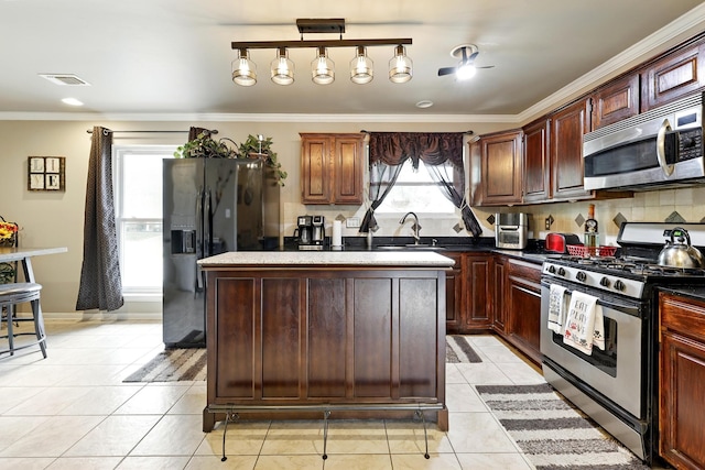 kitchen featuring visible vents, appliances with stainless steel finishes, a center island, light tile patterned floors, and ornamental molding