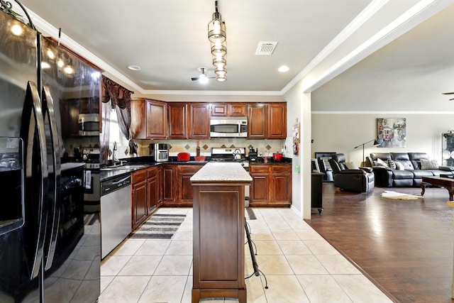 kitchen with a kitchen island, crown molding, appliances with stainless steel finishes, a sink, and open floor plan
