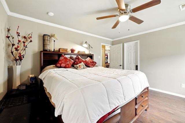 bedroom with ceiling fan, baseboards, wood finished floors, visible vents, and ornamental molding