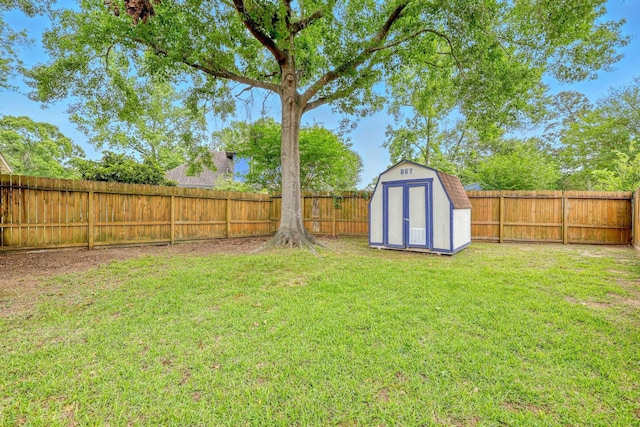 view of yard featuring an outdoor structure, a fenced backyard, and a storage unit