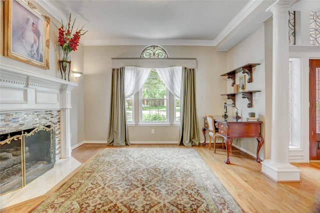living area featuring crown molding, decorative columns, and wood finished floors
