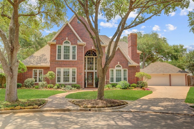 view of front facade with brick siding, a front lawn, a chimney, and concrete driveway