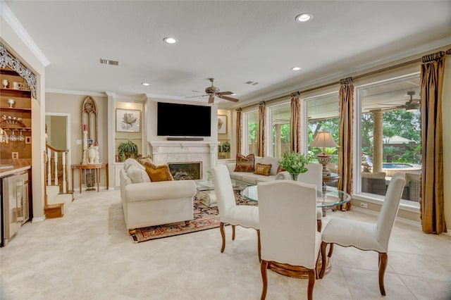 dining space featuring ceiling fan, a glass covered fireplace, wine cooler, visible vents, and ornamental molding