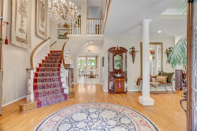 entrance foyer with ornate columns, baseboards, stairs, and wood finished floors