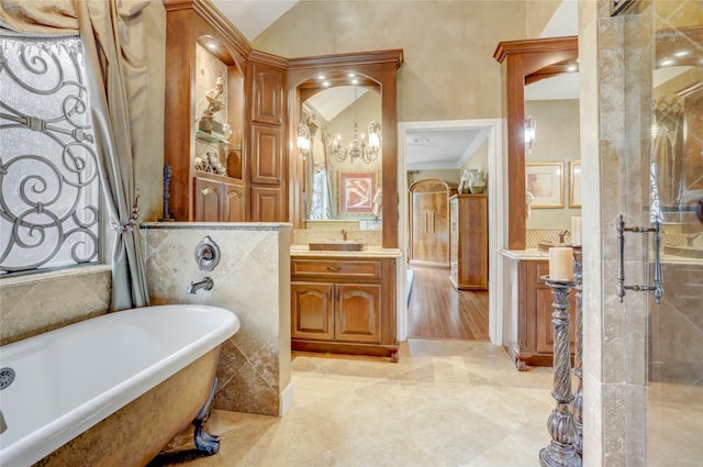 bathroom featuring marble finish floor, a freestanding bath, lofted ceiling, and vanity