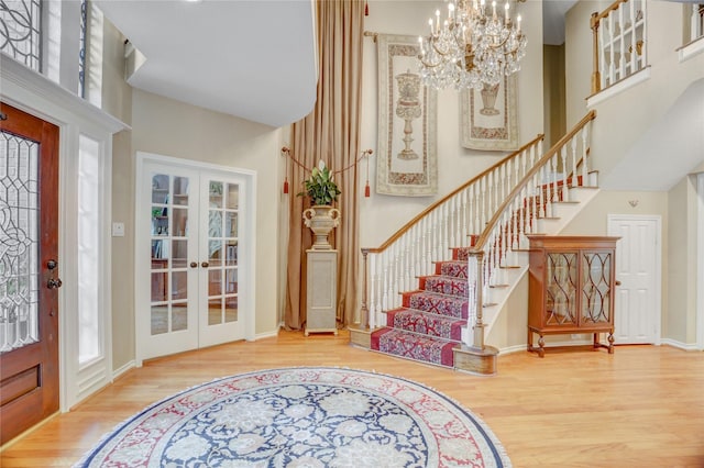 entrance foyer with french doors, wood finished floors, and a towering ceiling