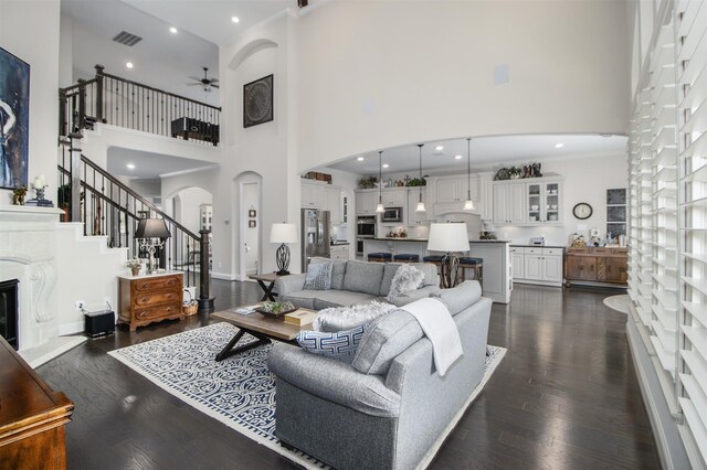 34119 Mill Creek Way, Pinehurst, TX 77362 - living area featuring a ceiling fan, arched walkways, dark wood finished floors, and a towering ceiling