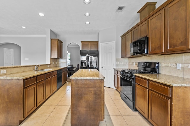 kitchen featuring a sink, arched walkways, backsplash, a kitchen island, and black appliances