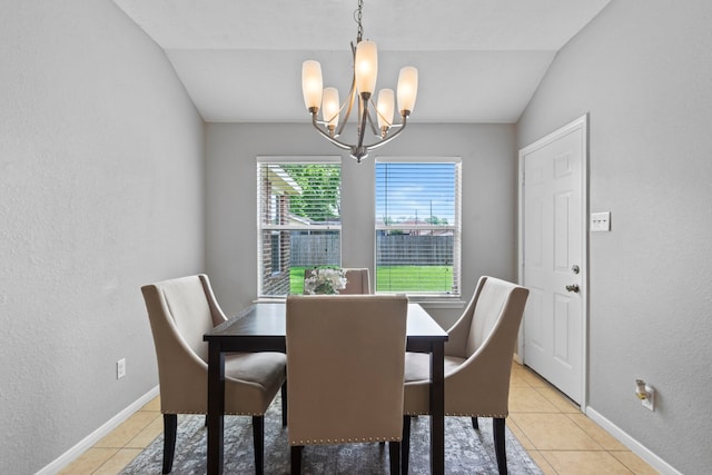 dining area with an inviting chandelier, light tile patterned floors, a textured wall, and vaulted ceiling