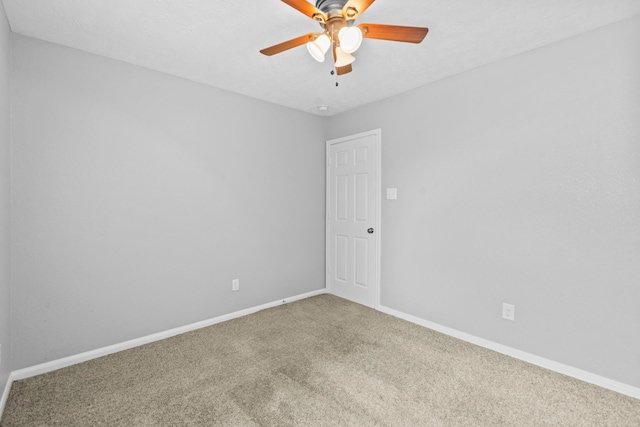 carpeted spare room featuring baseboards and a ceiling fan