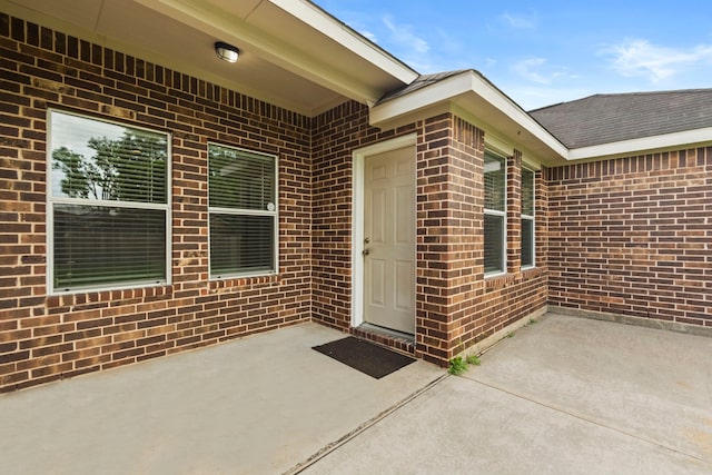 entrance to property featuring brick siding and a patio area