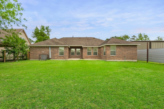 rear view of house with a lawn, cooling unit, and brick siding