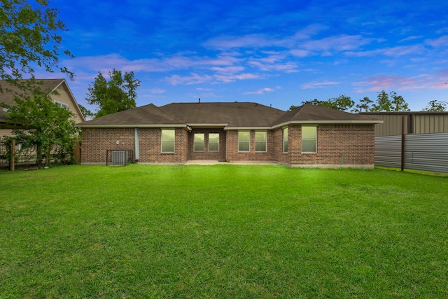 rear view of house featuring a yard and brick siding