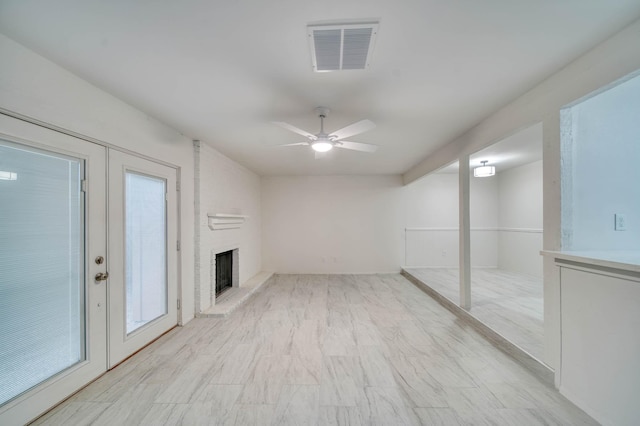unfurnished living room featuring a brick fireplace, a ceiling fan, and visible vents