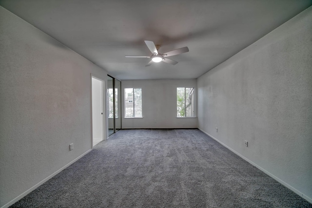 unfurnished room with carpet floors, a ceiling fan, a textured wall, and baseboards