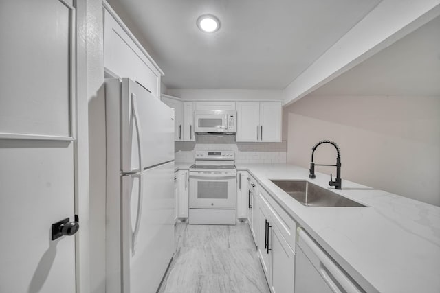 kitchen featuring white cabinets, light stone countertops, a sink, white appliances, and tasteful backsplash