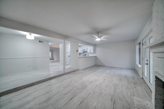 unfurnished living room featuring a ceiling fan, visible vents, and a fireplace