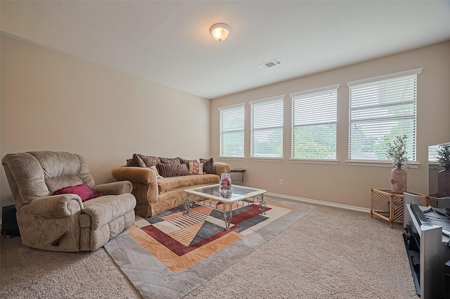 living area featuring baseboards, visible vents, and light carpet