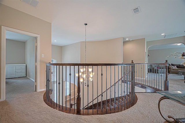 corridor with visible vents, carpet, a chandelier, and an upstairs landing