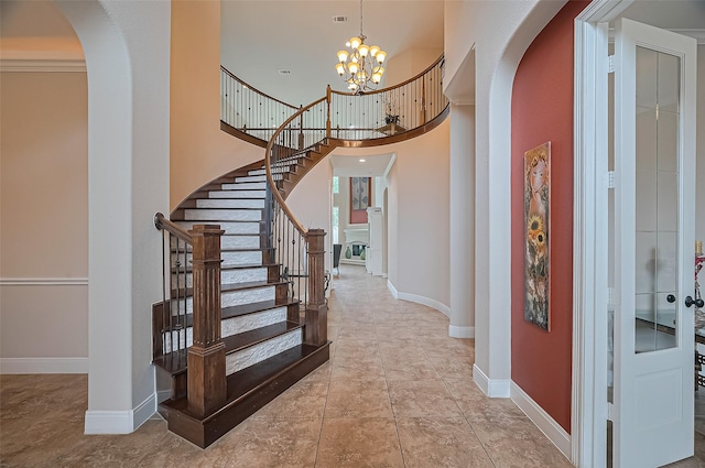 tiled foyer entrance featuring an inviting chandelier, arched walkways, stairs, and baseboards