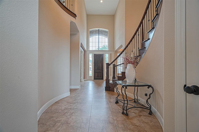 entryway featuring stairs, baseboards, and a towering ceiling